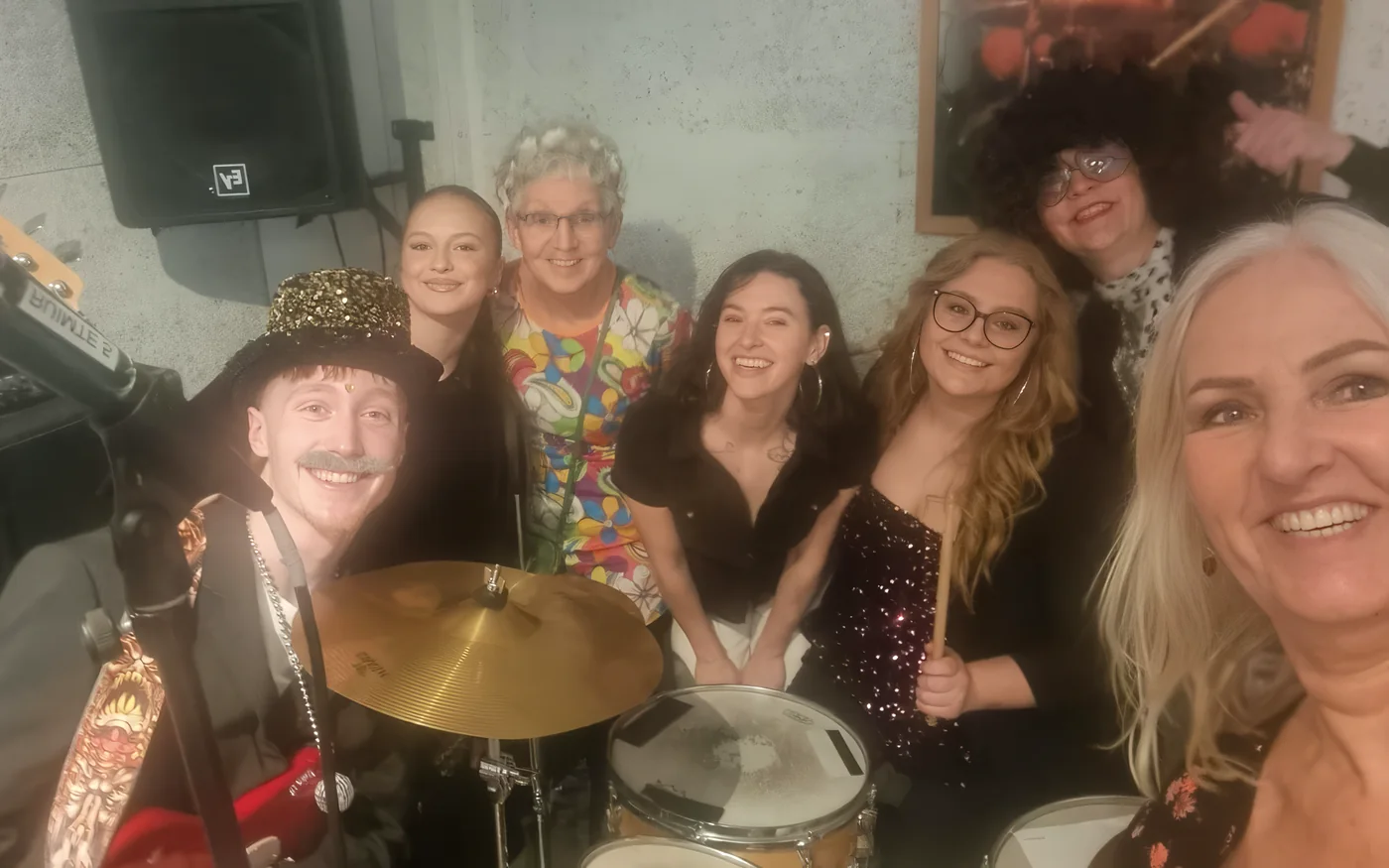 Verklede deelnemers poseren lachend achter het drumstel tijdens Clash Of The Chords