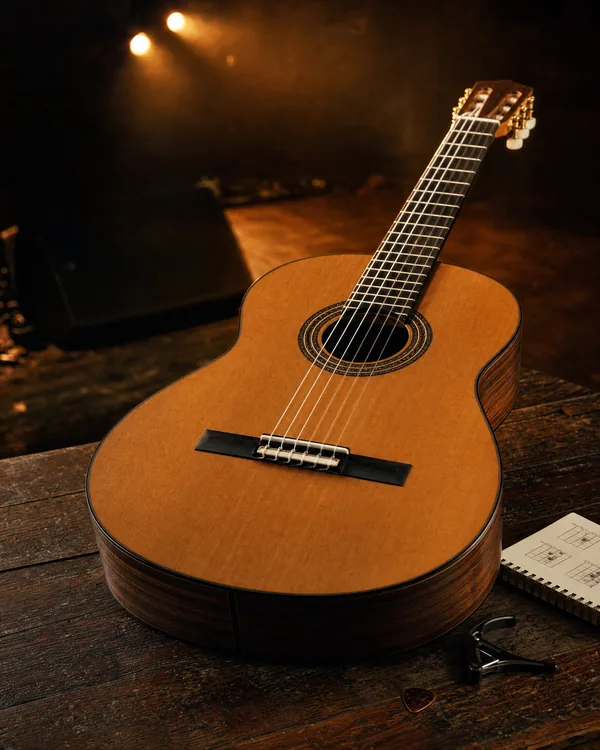 Klassieke gitaar met nylon snaren, capo en plectrum op tafel