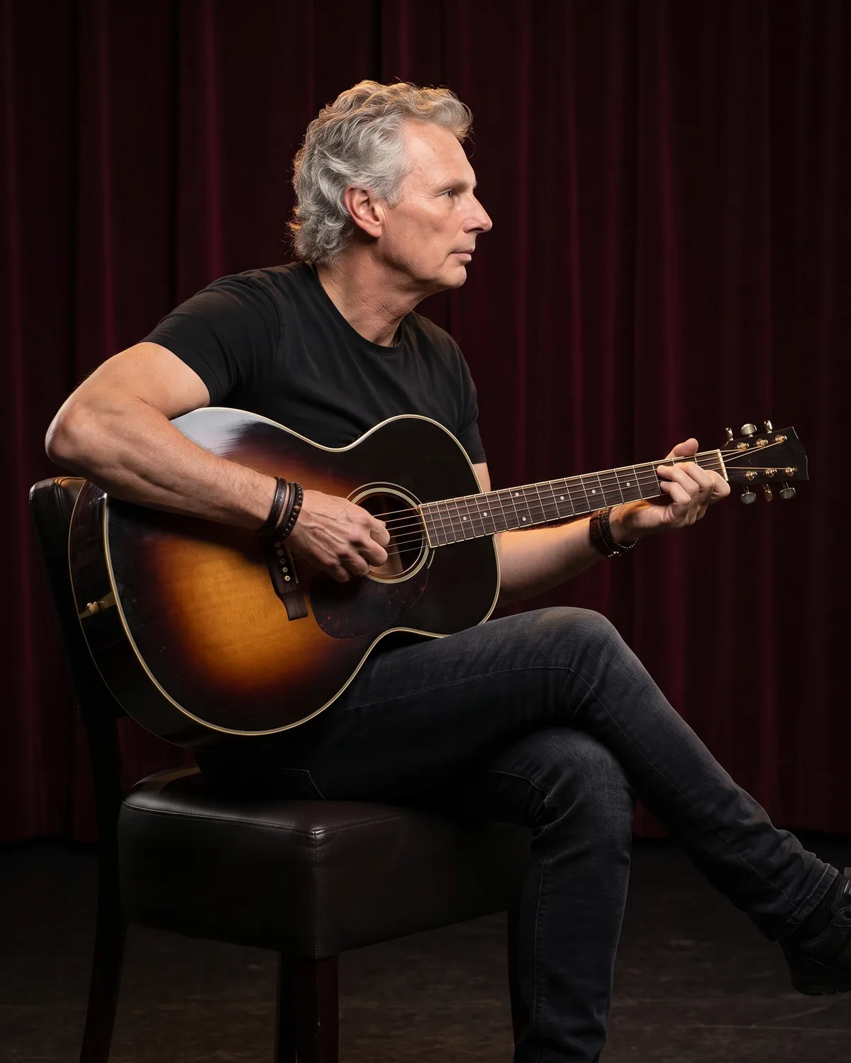 Wim Kingma van opzij, spelend op een sunburst akoestische gitaar
