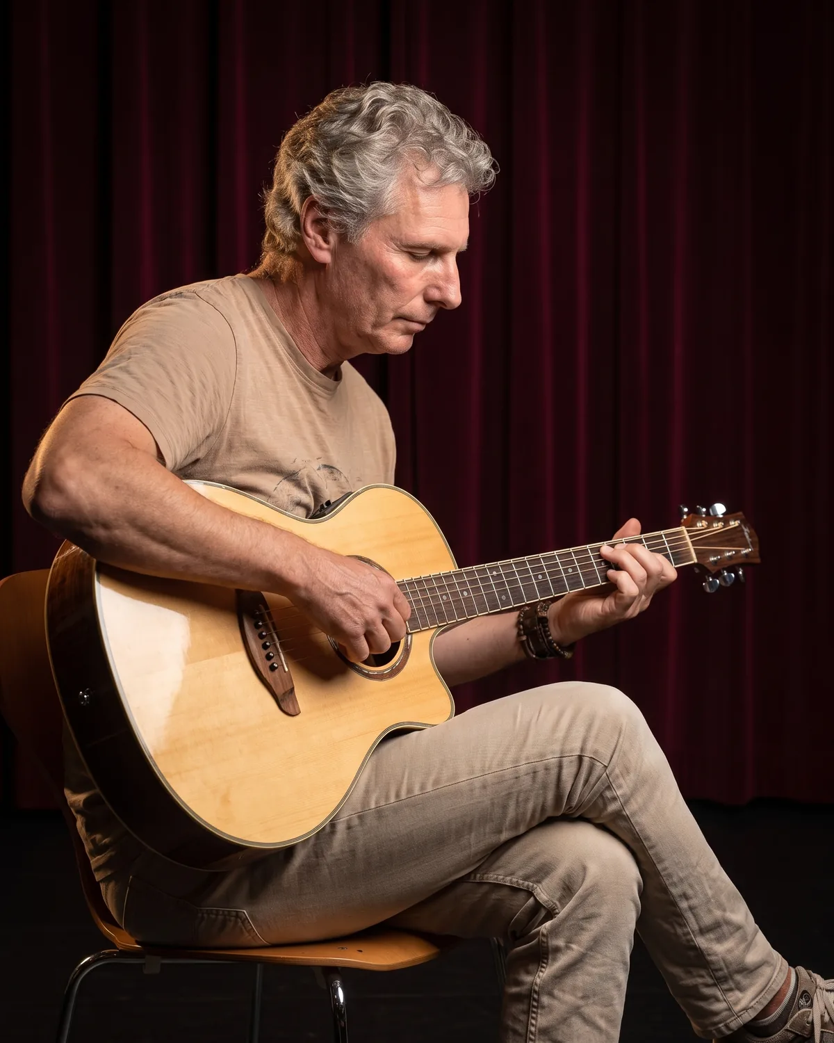 Wim Kingma speelt geconcentreerd op een akoestische gitaar met naturel bovenblad