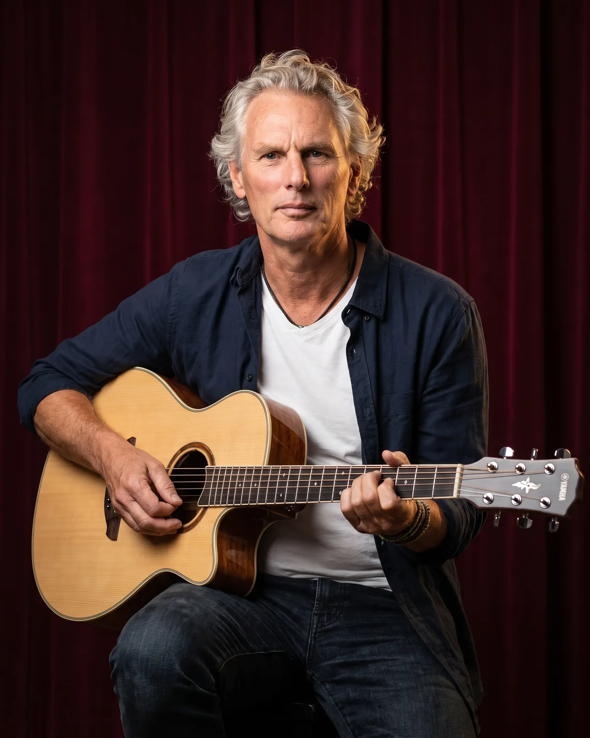 Gitaarleraar Wim Kingma kijkt in de camera met zijn akoestische gitaar op schoot